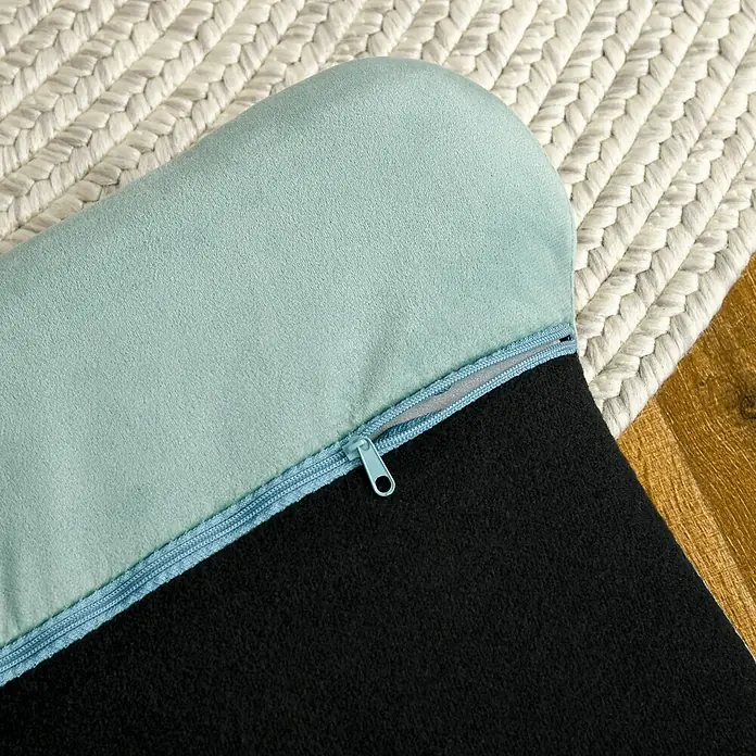 SONNENH Haustierbett - 98,5 x 60,5 x 35,5 cm, Textil, Grün - Hellblaues, weiches Kissen mit teilweise geöffnetem Reißverschluss, der schwarzen Stoff zeigt, auf einem Teppich.