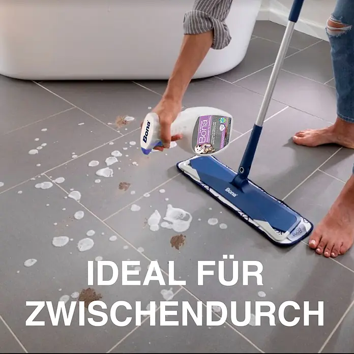 Bona Pet System Reinigungsmittel Tiefenreiniger für Hartböden - 1 l, Flasche mit Sprühkopf - Eine Person reinigt einen Fliesenboden mit Bona Sprühreiniger und einem Flachmopp.