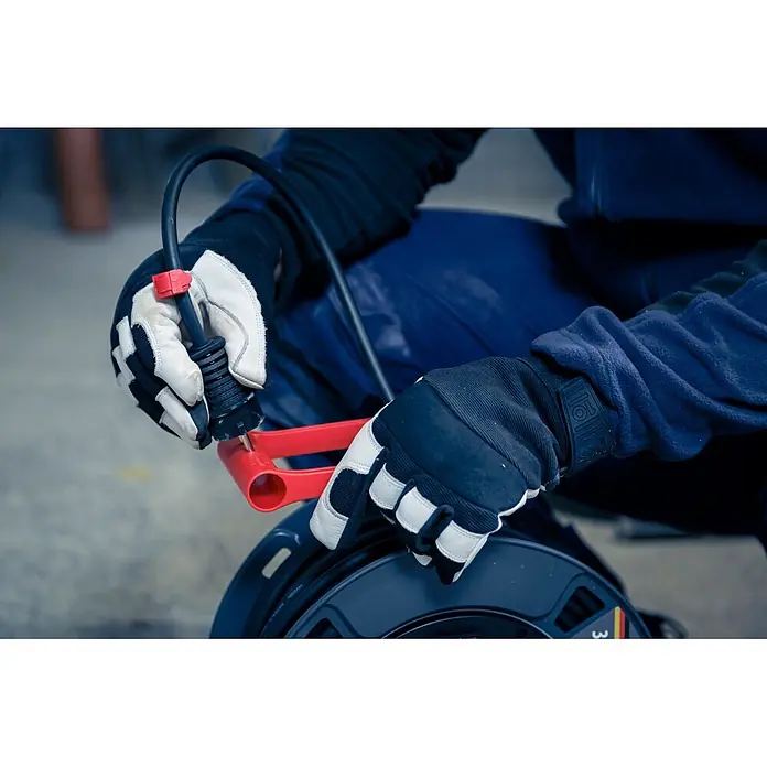 Brennenstuhl Kabeltrommel 300 KU 4100 - Kunststoff, 40 m, H07RN-F, IP44 - Person mit Arbeitshandschuhen wickelt ein schwarzes Kabel mit rotem Griff auf eine schwarze Kabeltrommel.