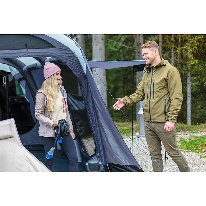 Brennenstuhl Verlängerungskabel Camping-CEE - 25 m, IP44, H07RN-F - Paar bereitet Campingplatz vor. Frau hält ein aufgerolltes Stromkabel mit blauen CEE-Steckern neben einem Campingzelt.