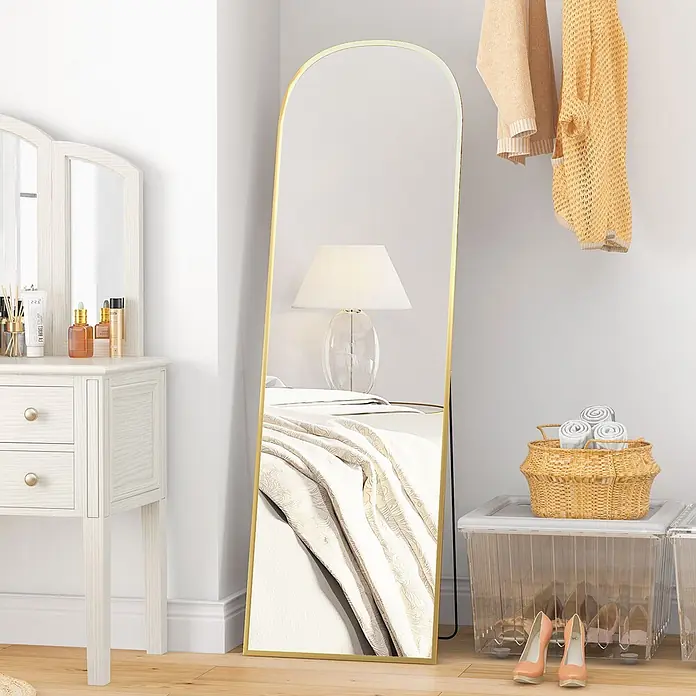 Homcom Standspiegel - Schwarz, Metall - Goldgerahmter Bogen-Ganzkörperspiegel in einem Schlafzimmer, der ein Bett und eine Lampe widerspiegelt.