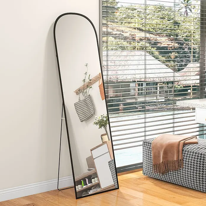 Homcom Standspiegel - Schwarz, Glas - Schwarz gerahmter Ganzkörperspiegel mit abgerundeter Oberseite, an eine Wand gelehnt.