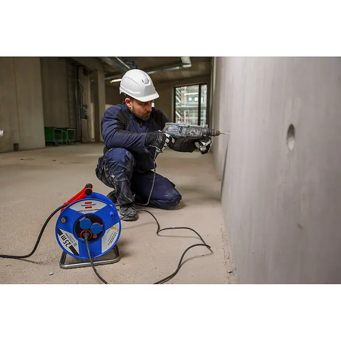 Brennenstuhl Garant Kabeltrommel - Kunststoff, 25 m, H07RN-F, IP44 - Blauer brennenstuhl Kabeltrommel auf einer Baustelle, versorgt einen Bohrer mit Strom.