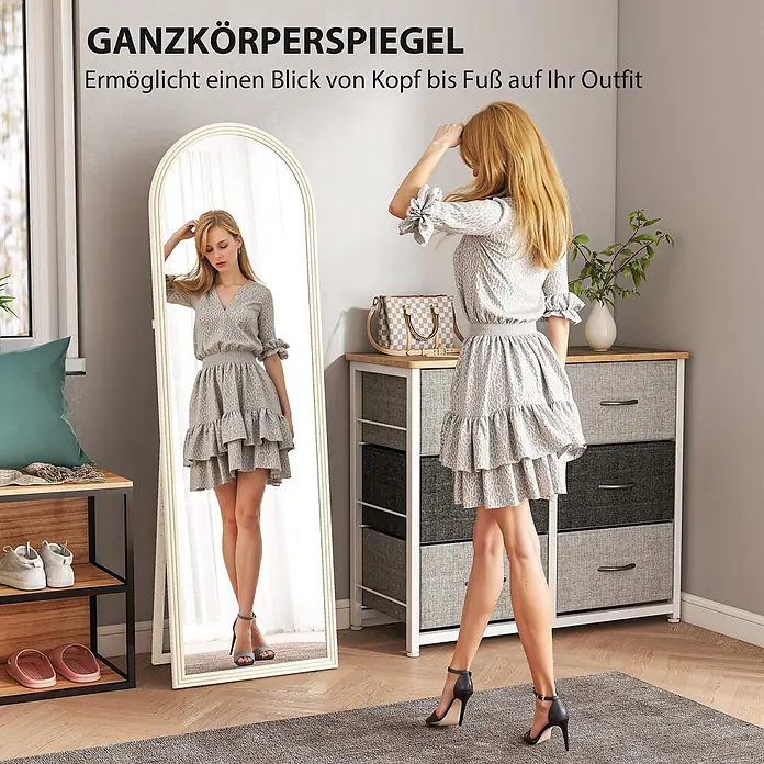 Homcom Standspiegel - Weiß, Glas - Bogenförmiger Ganzkörperspiegel mit cremefarbenem Rahmen, von einer Frau zum Prüfen ihres Outfits verwendet.