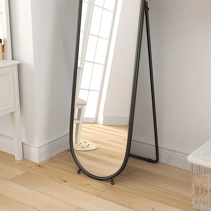 Homcom Standspiegel - Transparent, Glas - Stehender Ganzkörperspiegel mit schwarzem Rahmen auf hellem Holzfußboden in einem hellen Raum.