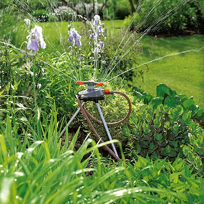 Gardena Classic Kreisregner Samba - Kunststoff, Max. Regnerfläche: 250 m² - Gartenbewässerung mit einem Rasensprenger auf einem Stativ, der das umliegende Grün mit Wasser versorgt.