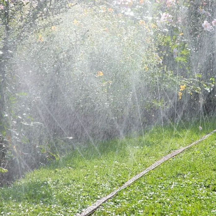 Gardena Schlauchregner - Braun, 15 m - Die Bewässerung des Gartens mit einem Rasensprenger, der Wasser auf das grüne Gras und die Pflanzen sprüht. Die Gartenbewässerung sorgt für gesunde Vegetation.