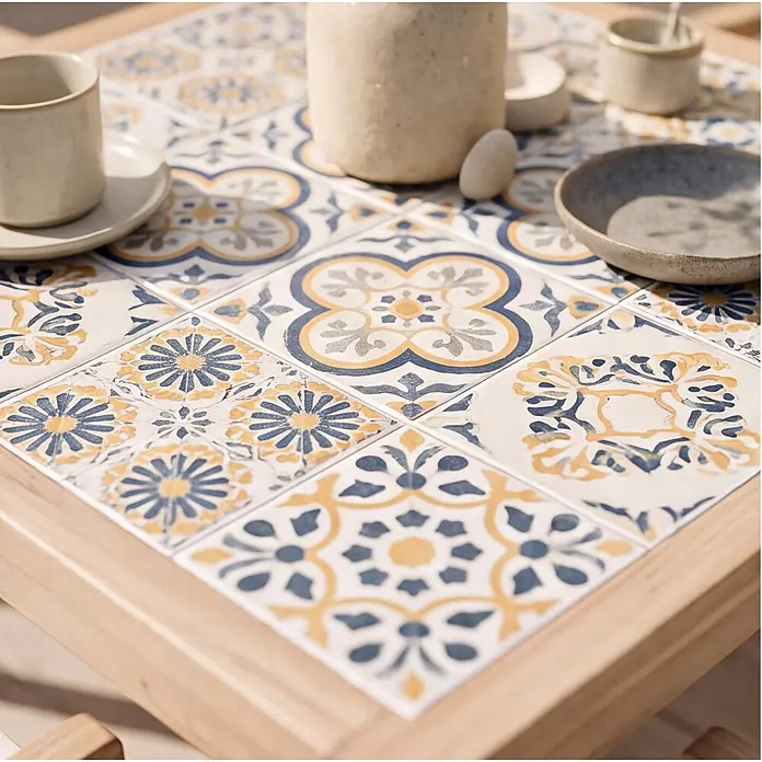 Set aus Gartentisch und -stühlen für 4 Personen aus Akazienholz und Keramik FARO -  - Nahaufnahme eines Tisches mit weiß-blau-gelb gemusterten Fliesen im mediterranen Stil, mit Tassen und Schalen.