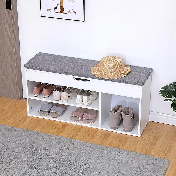 Happy Garden Schuhschrank ALAN - Weiß - Weißer Schuhschrank mit grauer Stoffauflage, mehreren offenen Fächern für Schuhe und einer Schublade. Darauf stehen Schuhe und ein Strohhut.
