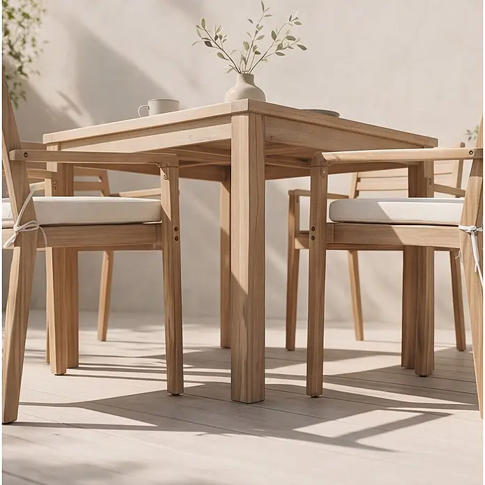 Set aus Gartentisch und -stühlen für 4 Personen aus Akazienholz und Keramik FARO -  - Sonnenbeschienene Outdoor-Essgruppe aus hellem Holz mit quadratischem Tisch und Stühlen mit weißen Sitzkissen.