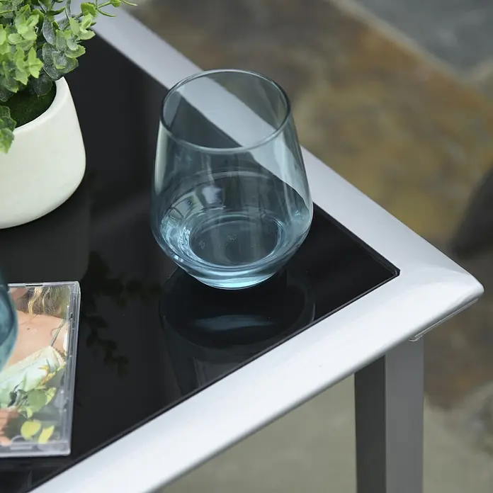 Outsunny Gartenliegen-Set 3-tlg. mit Tisch - Schwarz, Silber, Metall - Blaues Trinkglas mit Wasser auf einem dunklen Tisch mit silbernem Rahmen.
