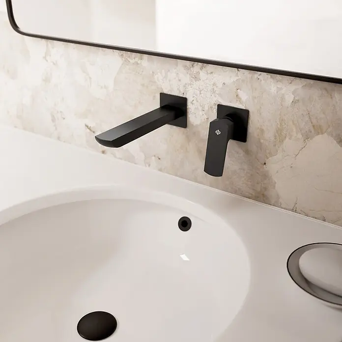 IO Grifo de lavabo empotrado Marriot - Negro - Grifo de pared negro mate con caño y maneta sobre un lavabo blanco con desagüe negro.