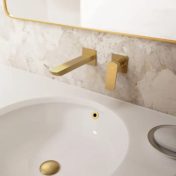 IO Grifo de lavabo empotrado Marriot - Oro - Lavabo de baño moderno con grifo, maneta, desagüe y rebosadero dorados mate de pared, sobre una pared de mármol.