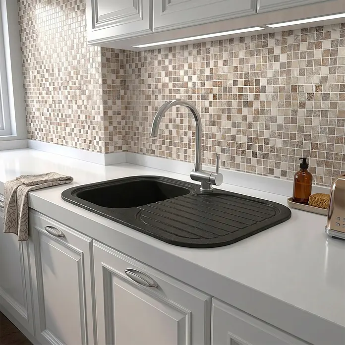 Poalgi Fregadero encastrable Coral - 48,5 x 81 cm, Negro - Fregadero de cocina de composite negro con escurridor integrado y grifo cromado, instalado en una encimera de cocina blanca.