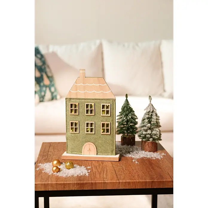 Dekoartikel LED Filzhaus - 1 Stk., Sortiert, 18 x 5 x 29 cm - Festliches Weihnachtsdekorationsset mit einem grünen Filzhaus, zwei Mini-Bäumen, Goldkugeln und Kunstschnee auf einem Holztisch.