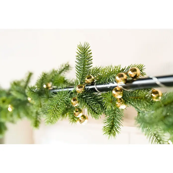 Perlenkette XXL - 2 x 270 cm, Kunststoff, Gold - Grüne künstliche Weihnachtsgirlande mit goldenen Kugeln um eine schwarze Stange gewickelt.