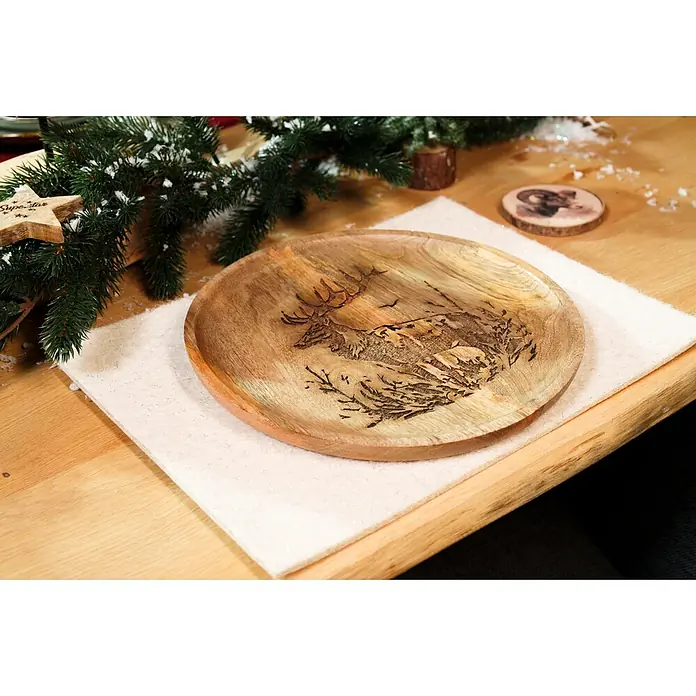 Platzset - 1 Stk., Sortiert, 28 x 38 cm - Runder Servierteller aus Holz mit graviertem Hirschmotiv, auf einem weißen Läufer inmitten festlicher Winterdekoration.