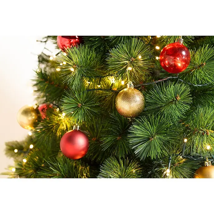 Christbaumkugel-Set - Gold, Kunststoff, 48 Stk., Durchmesser: 6 cm - Nahaufnahme eines grünen künstlichen Weihnachtsbaums, geschmückt mit roten und goldenen Kugeln und warmen Lichterketten.