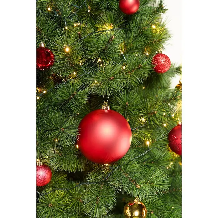 Christbaumkugel-Set - Rot, Kunststoff, 48 Stk., Durchmesser: 6 cm - Eine detaillierte Ansicht eines grünen künstlichen Weihnachtsbaums, geschmückt mit roten und goldenen Kugeln und leuchtenden Lichterketten.