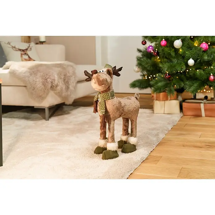 Dekofigur Weihnachtselch - L x B x H: 39 x 13 x 80 cm, Textil - Braune Plüsch-Rentier-Dekoration mit grünem Schal und Stiefeln, auf einem Teppich in einem festlichen Raum stehend.