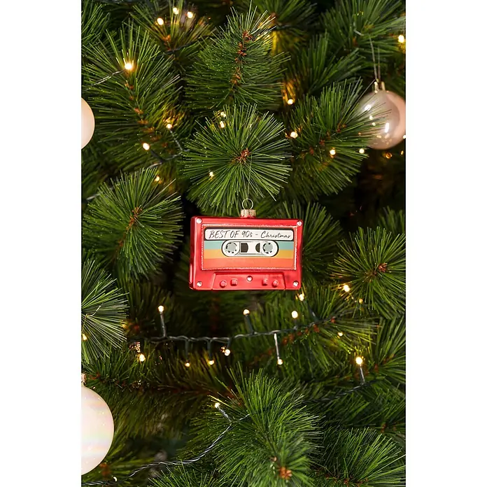 Christbaumschmuck Kassette - Rot, Glas, 10 x 2 x 7 cm - Roter Kassetten-Weihnachtsschmuck mit der Aufschrift „BEST OF 90s – Christmas“ an einem beleuchteten grünen Weihnachtsbaum.