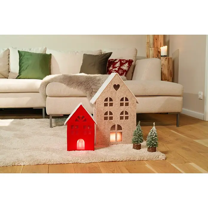 Dekoartikel LED Filzhaus - 1 Stk., Sortiert, 17,5 x 8,5 x 30,5 cm - Zwei Filzhaus-Laternen, rot und beige, mit verschneiten Miniaturbäumen, als festliche Winterdeko auf einem Teppich.