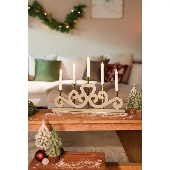 Markslöjd LED-Lichterbogen Eneby - L x B x H: 47 x 5 x 36 cm, Warmweiß, Greige - Creme-farbener 5-Kerzen-Adventsleuchter mit goldenen Akzenten und Elektrokerzen auf einem Holztisch mit Weihnachtsdeko.