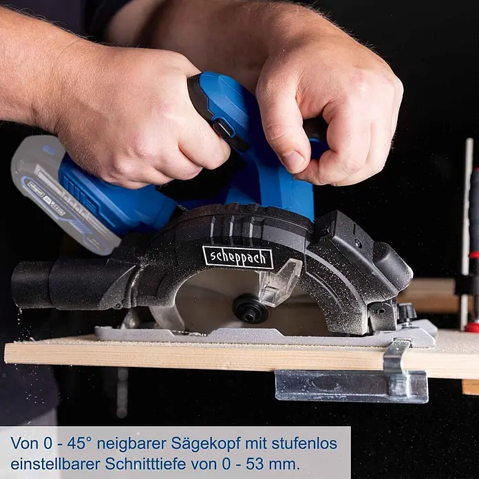 Scheppach IXES 20V Akku-Handkreissäge C-HCS165-X - 20 V, Durchmesser Sägeblatt: 165 mm - Nahaufnahme von Händen, die eine blau-schwarze Akku-Kreissäge bedienen, die Holz schneidet und Sägemehl erzeugt. Mit 0-45° neigbarem Kopf und 0-53mm Schnitttiefe.