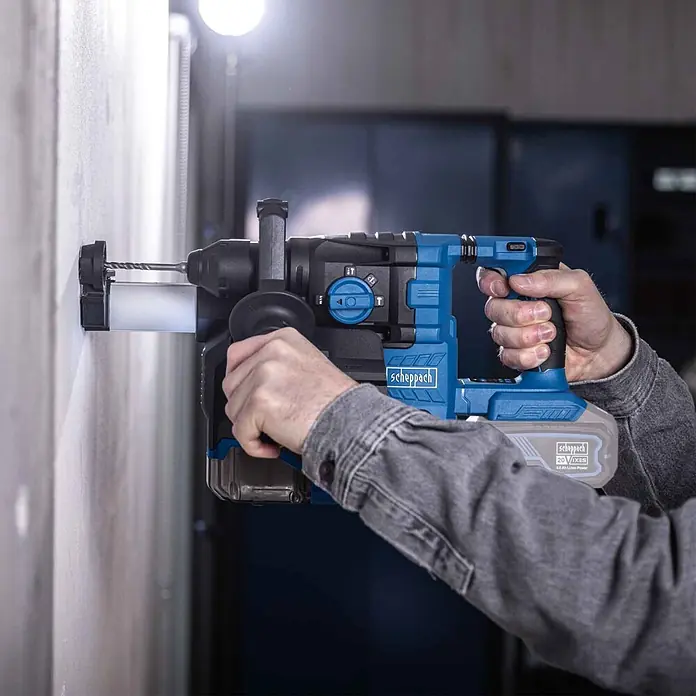 Scheppach IXES 20V Akku-Kombihammer - 20 V, Ohne Akku, 2,8 J - Eine Person benutzt einen blau-schwarzen Scheppach Akku-Bohrhammer mit 20V Akku zum Bohren in eine helle Wand.