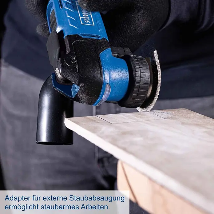 Scheppach IXES 20V Akku-Multifunktionswerkzeug C-MT40-X - 20 V - Blau-schwarzes Scheppach Multitool mit Staubabsaugadapter schneidet eine Fliese.