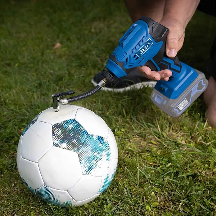 Scheppach IXES 20V Akku-Luftpumpe C-AC20-X - Max. Druck: 7 bar - Blauer Scheppach Akku-Kompressor pumpt einen weiß-blauen Fußball auf Gras auf.