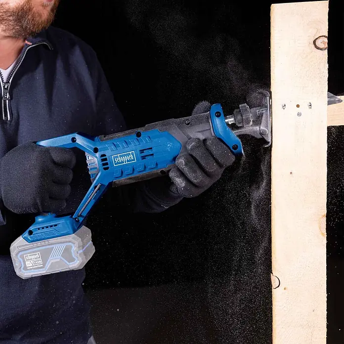 Scheppach IXES 20V Akku-Säbelsäge C-RS100-X - 20 V, Hublänge: 20 mm - Blaue akkubetriebene Scheppach Säbelsäge beim Holzschnitt.