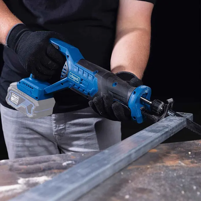 Scheppach IXES 20V Akku-Säbelsäge BC-RS250-X - 20 V, Ohne Akku, Hublänge: 28 mm - Blaue und schwarze Scheppach Akku-Säbelsäge schneidet einen Metallbalken. Eine Person bedient das Gerät mit Handschuhen.