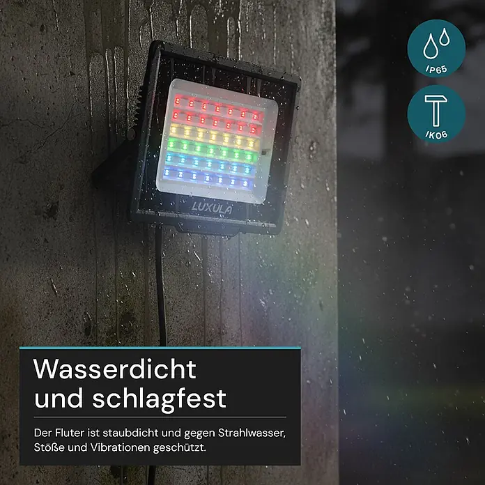 Luxula LED-Strahler - 50 W, IP65 - Schwarzer LUXULA LED-Fluter mit farbigen Lichtern an nasser Betonwand, betont wasserdichte und stoßfeste Eigenschaften.