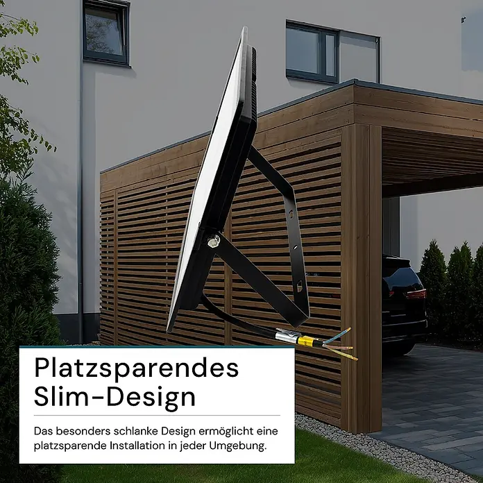Luxula LED-Strahler - 300 W, 30.000 lm, 4.000 K, IP65 - Schwarzer, schlanker LED-Fluter mit freiliegenden Kabeln, draußen vor modernem Gebäude und Carport montiert, betont platzsparendes Design.