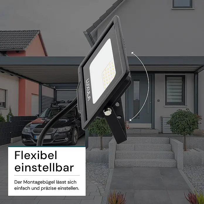 Luxula LED-Strahler - 20 W, 2.000 lm, 3.000 K, IP65 - Schwarzer LUXULA LED-Flutlichtstrahler mit verstellbarem Montagebügel, draußen vor einem Haus positioniert.