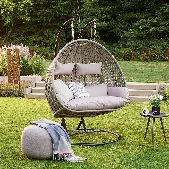 Home Deluxe Hängesessel Kissen TWIN Grau -  - Doppelter grauer Rattan-Eier-Gartenschaukelstuhl mit hellgrauen Kissen, passendem Pouf und kleinem schwarzem Beistelltisch.
