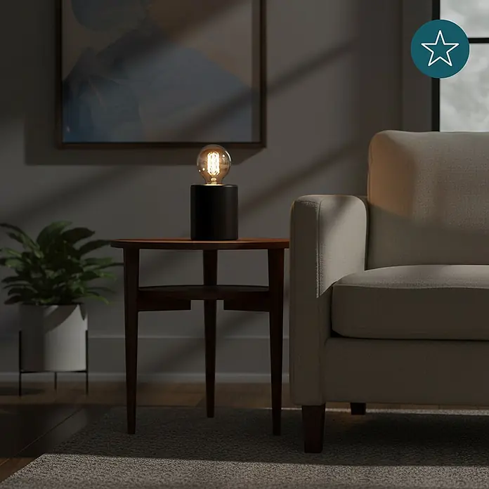 Luxula Deko-Tischleuchte E27 Fassung Modern Design Metall Nachttischleuchte -  - Schwarze zylindrische Tischleuchte mit freiliegender Edison-Birne auf einem Holztisch, beleuchtet eine gemütliche Wohnzimmerszene.
