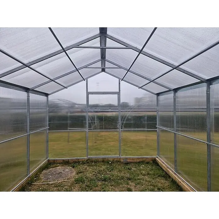 Garten Dream Gewächshaus Flora, 10mm Polycarbonat - 300 x 800 cm, Material Seitenwand: Kunststoff, 10 mm, Silber - Innenansicht eines Gewächshauses mit Metallrahmen und transparenten Platten, mit Grasboden innen und außen.