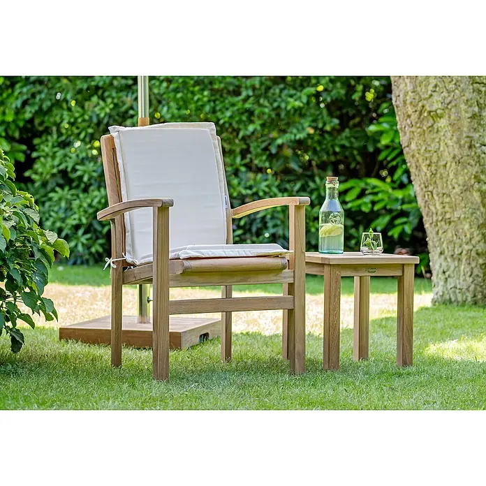 Gartenstuhl Auflage mit Rücken Bordeaux rot Dralon waschbar -  - Teak-Gartenstuhl mit cremefarbenen Kissen und passendem Beistelltisch. Auf dem Tisch stehen eine Flasche Zitronenwasser und ein Glas.