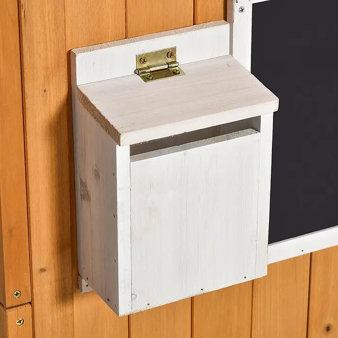 Outsunny Spielhaus - Holz, Naturholz - Weißer Holzbriefkasten mit Klappdeckel an brauner Holzwand, neben einer schwarzen Fläche.