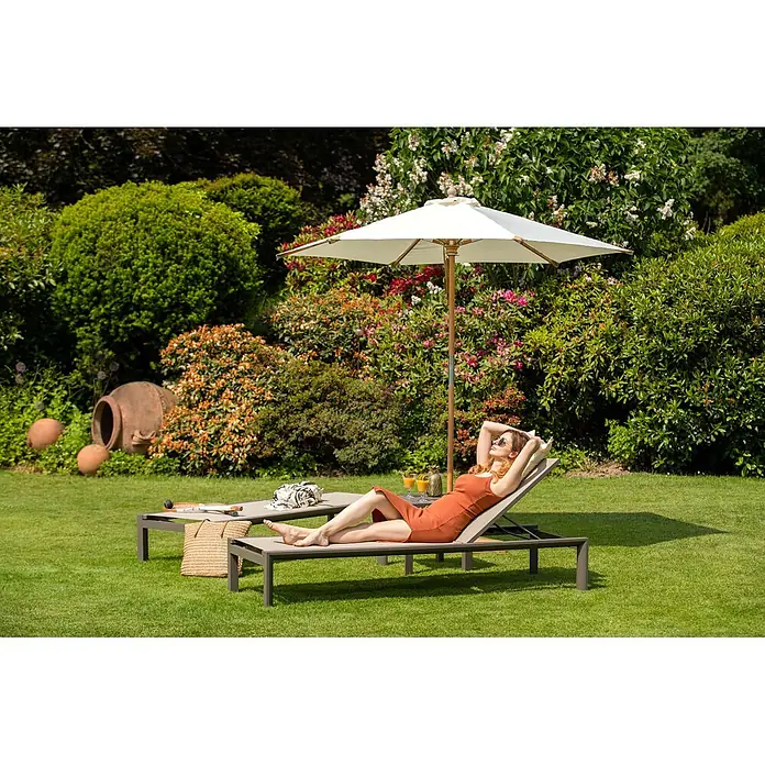Kai Wiechmann Garten-Beistelltisch - Quadratisch, Taupe - Eine Frau entspannt auf einer modernen Sonnenliege mit dunkelgrauem Gestell und hellbeigem Stoff in einem sonnigen Garten.