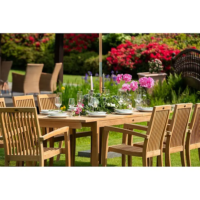 Kai Wiechmann Gartenstuhl - Teakholz, Stapelbar, Naturbelassen - Hölzerne Garten-Essgruppe mit Tisch und Stühlen, festlich gedeckt für eine Mahlzeit im Grünen.