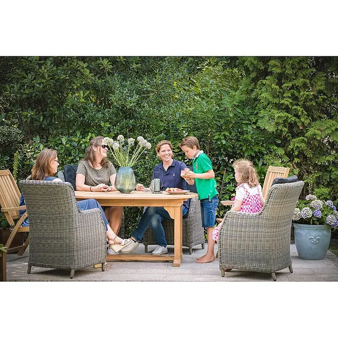 Teak Ausziehtisch oval 180 x 100 cm wetterfest erweiterbar -  - Teak-Gartentisch mit geflochtenen Stühlen, von einer Familie im Garten genutzt.