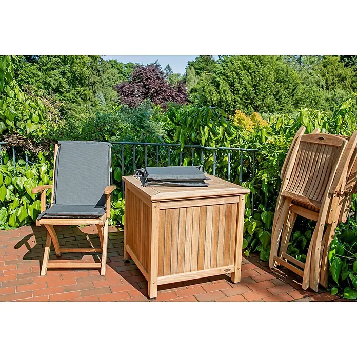 Auflage für Gartenstuhl grün Dralon waschbar perfekte Verarbeitung -  - Teak-Gartenmöbelset auf einer Ziegelterrasse. Bestehend aus Stuhl mit grauem Kissen, Aufbewahrungsbox mit Kissen und zusammengeklappten Stühlen.