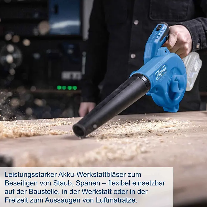 Scheppach IXES 20V Akku-Gebläse C-WBL180-X - 20 V, Ohne Akku - Eine Person nutzt einen blau-schwarzen Scheppach Akku-Werkstattbläser, um Sägespäne von einer Holzbank zu entfernen.