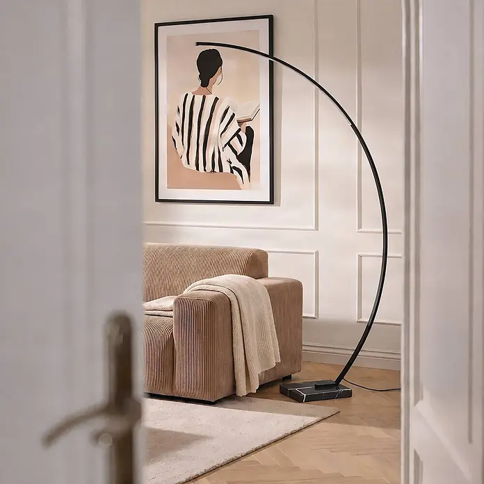 Lindby LED Stehlampe in schwarz, Bogenlampe Wohnzimmer -  - Schwarze Bogen-Stehlampe mit Marmorsockel, die ein beiges Sofa in einem Wohnzimmer beleuchtet.
