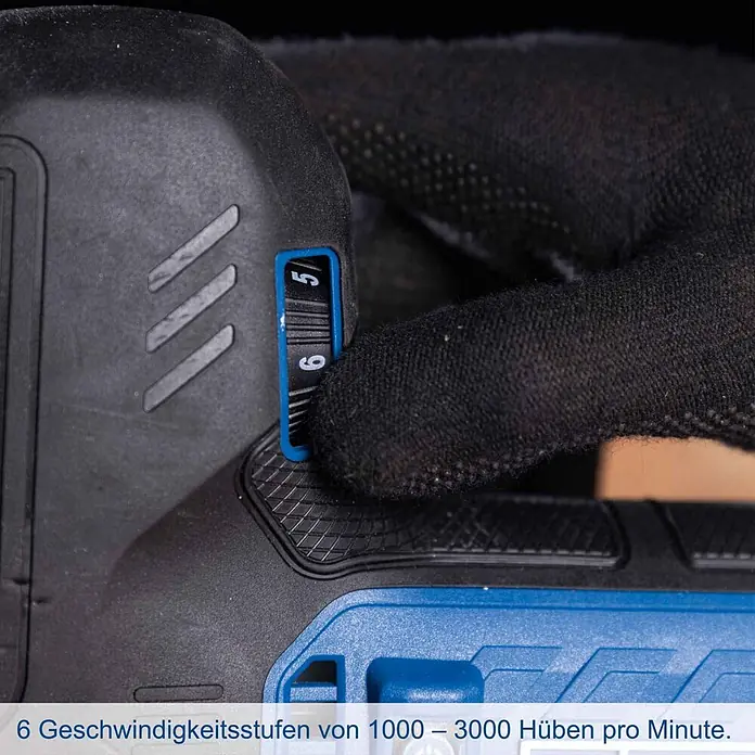 Scheppach IXES 20V Akku-Stichsäge BC-JS254-X - 20 V, Ohne Akku, Leerlaufhubzahl: 0 /min - 3.000 /min - Hand im schwarzen Handschuh stellt blaues Geschwindigkeitsrad am dunkelgrauen Elektrowerkzeug auf Stufe '6'. Die Skala zeigt '5' und '6'.