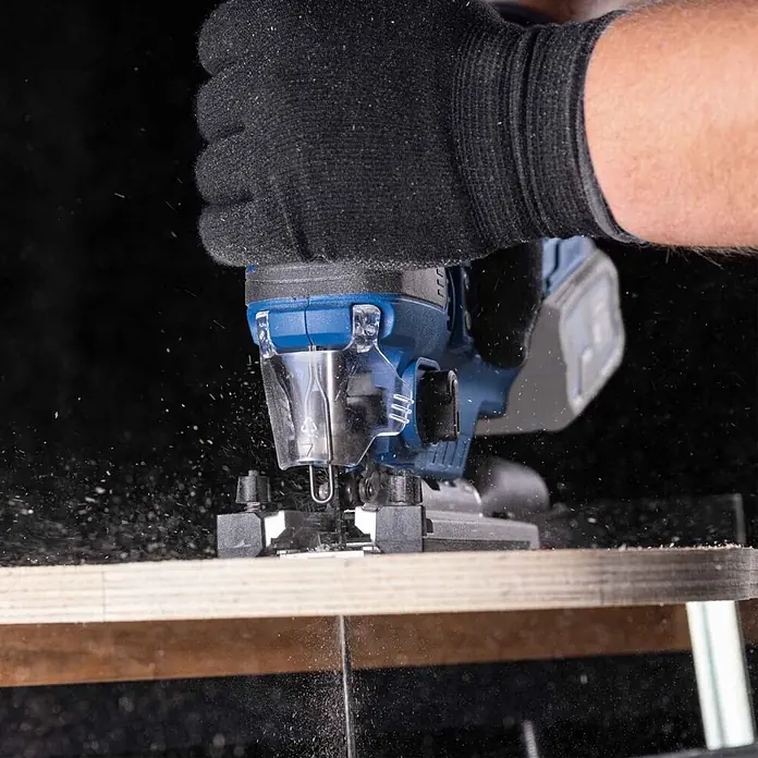 Scheppach IXES 20V Akku-Stichsäge BC-JS254-X - 20 V, Ohne Akku, Leerlaufhubzahl: 0 /min - 3.000 /min - Blaue Akku-Stichsäge schneidet Holz, von Handschuhhand geführt, mit fliegenden Spänen.