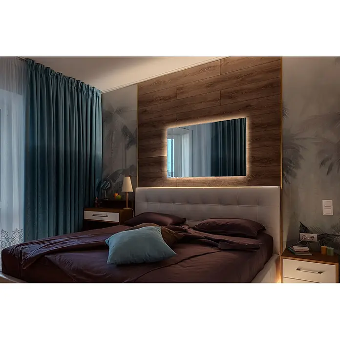 Tulup Wandspiegel -  - Schlafzimmer mit Bett, hellem gepolstertem Kopfteil, dunkelvioletter Bettwäsche und blauem Kissen. Ein hinterleuchteter Spiegel ist über dem Bett in Holzpaneelen eingelassen.